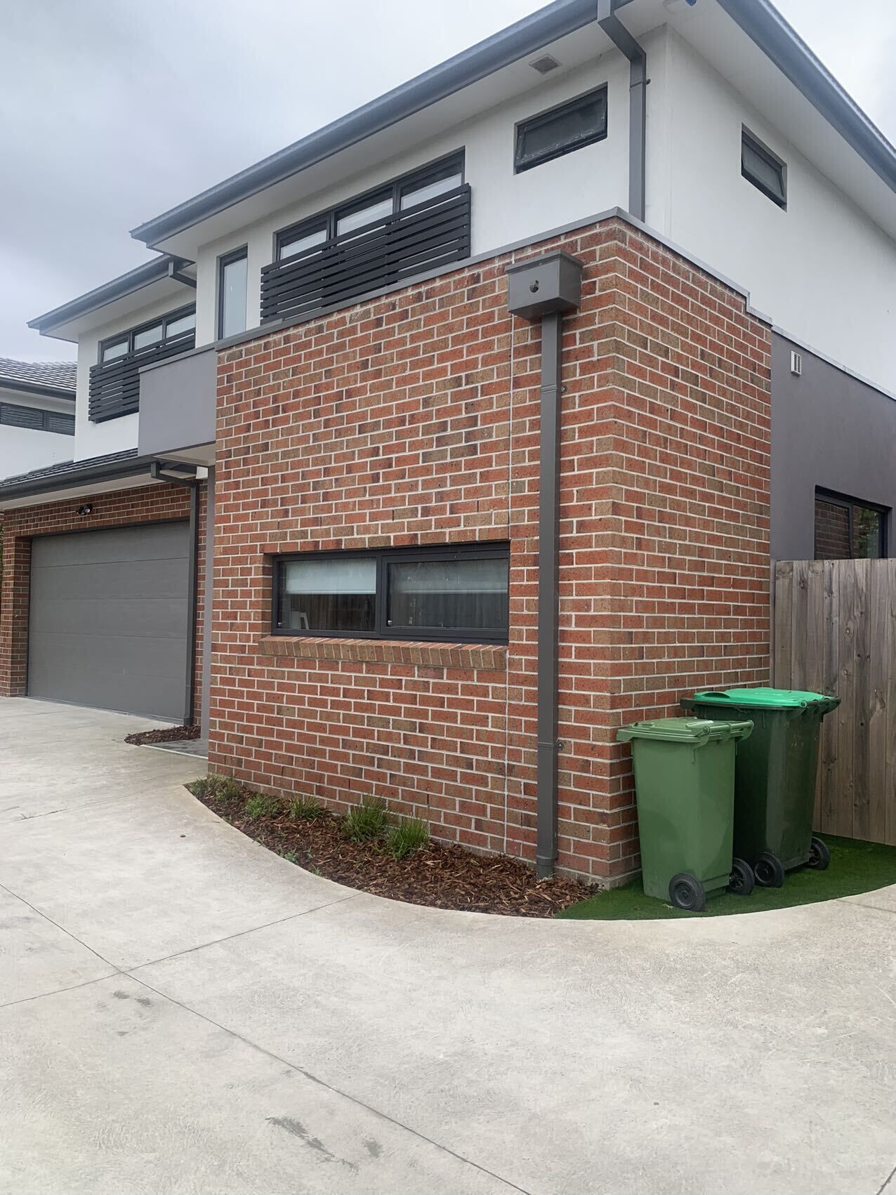 Une maison moderne à deux étages, avec une façade en briques et un garage.