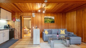 A wooden interior with a sofa, coffee table, and a painting on the wall. - Cosy holiday apartment near the slopes (Itter)