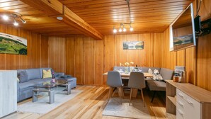 A cozy cabin interior with a dining table, chairs, a sofa, and a kitchenette. - Cosy holiday apartment near the slopes (Itter)