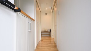 Un couloir étroit avec un plancher en bois et des murs blancs.