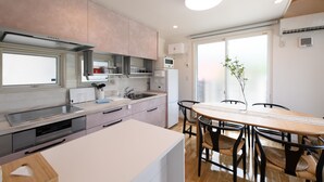 Une cuisine moderne avec un coin repas, dotée d’une grande fenêtre, d’appareils électroménagers intégrés et d’un îlot central.