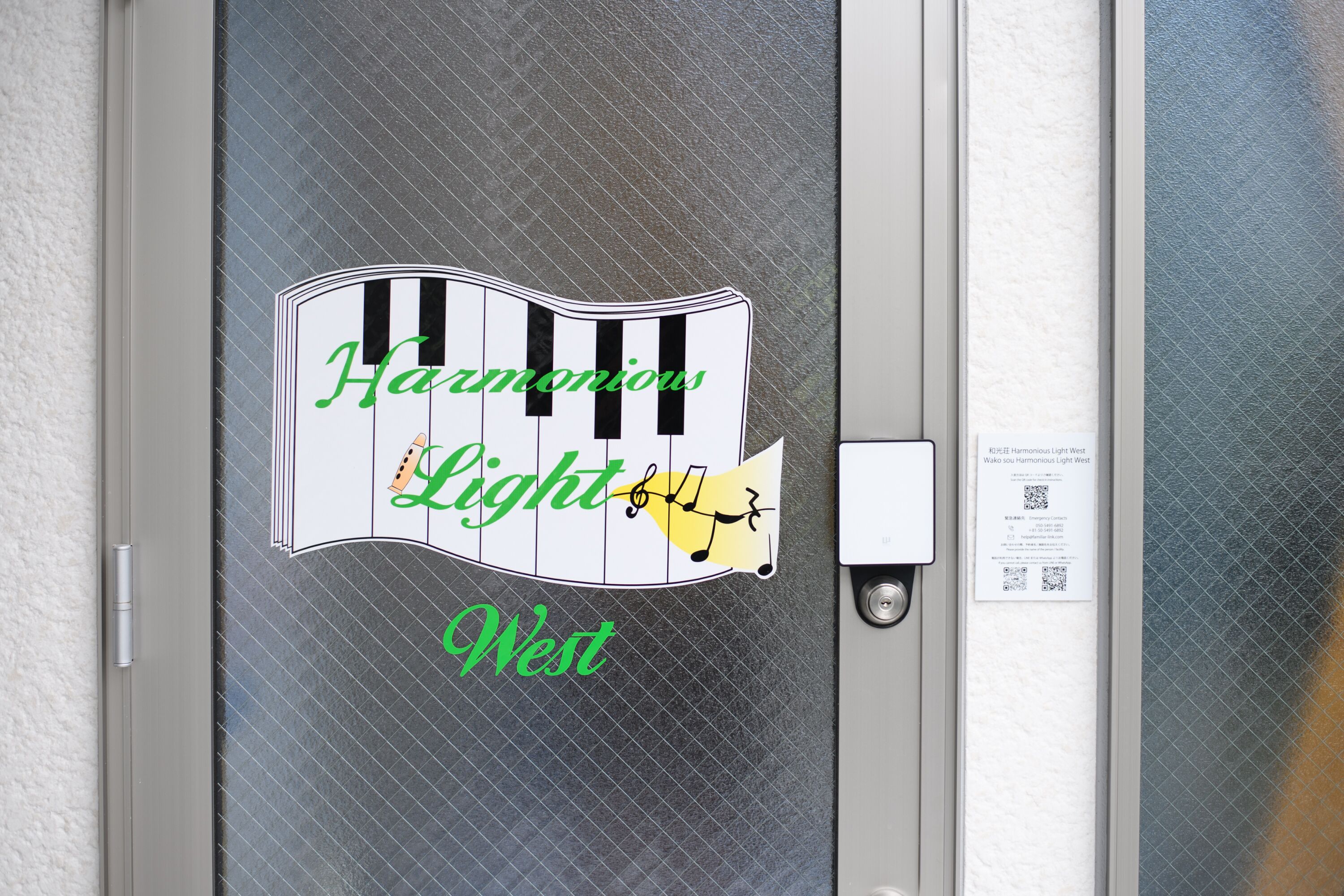 A door with a piano-themed sign that reads "Harmonious Light West."