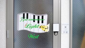 A door with a piano-themed sign that reads "Harmonious Light West."