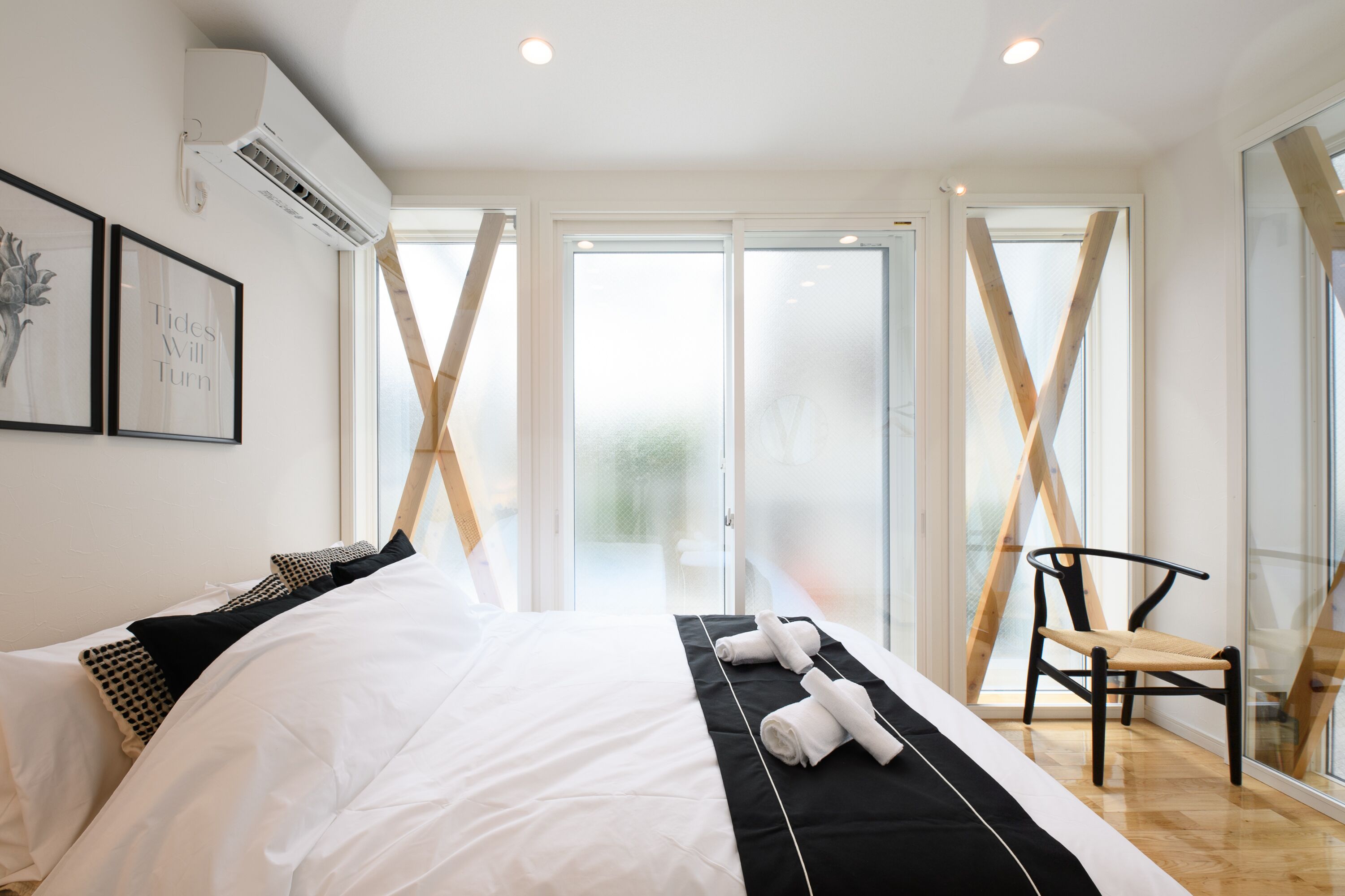 A modern hotel room with a large bed, a chair, and a view through a glass door.