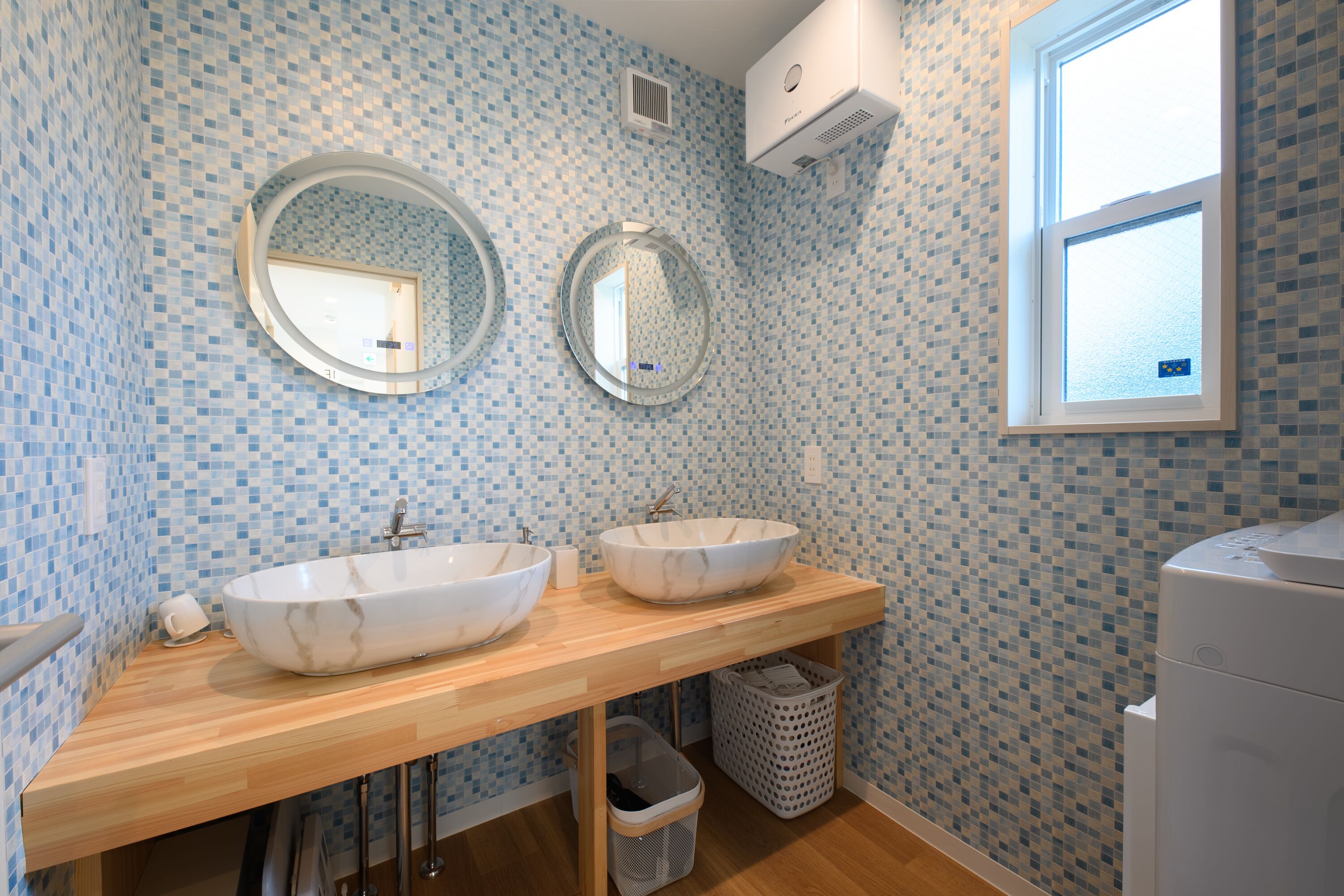 A bathroom with two sinks, a mirror, a window, and a tiled backsplash.