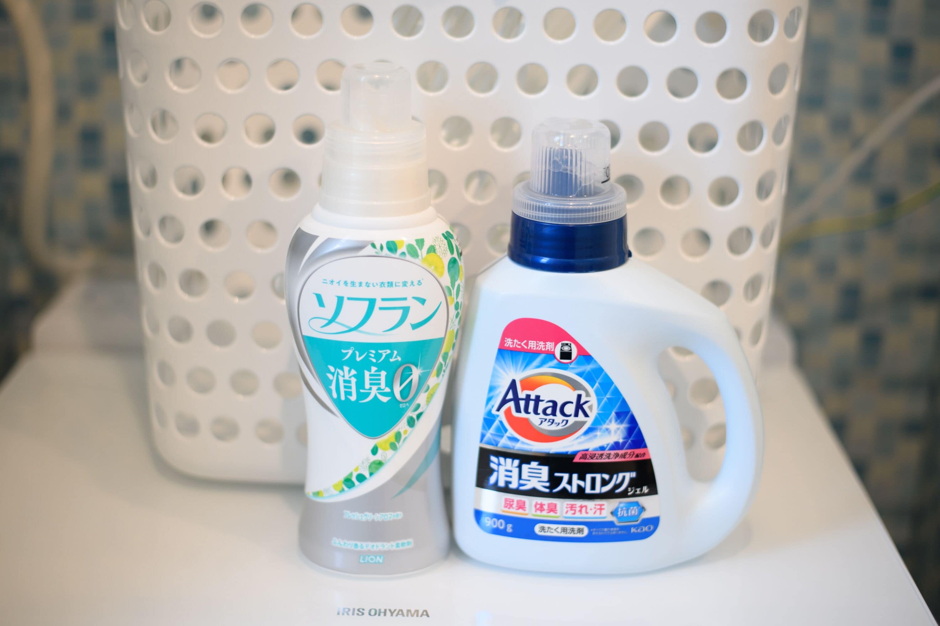Deux bouteilles de produits de nettoyage sur une surface blanche, avec un panier ajouré en arrière-plan.