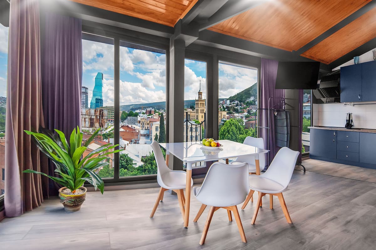 Ein moderner Essbereich mit großem Fenster, einem Blumentopf und einem Tisch mit Stühlen.