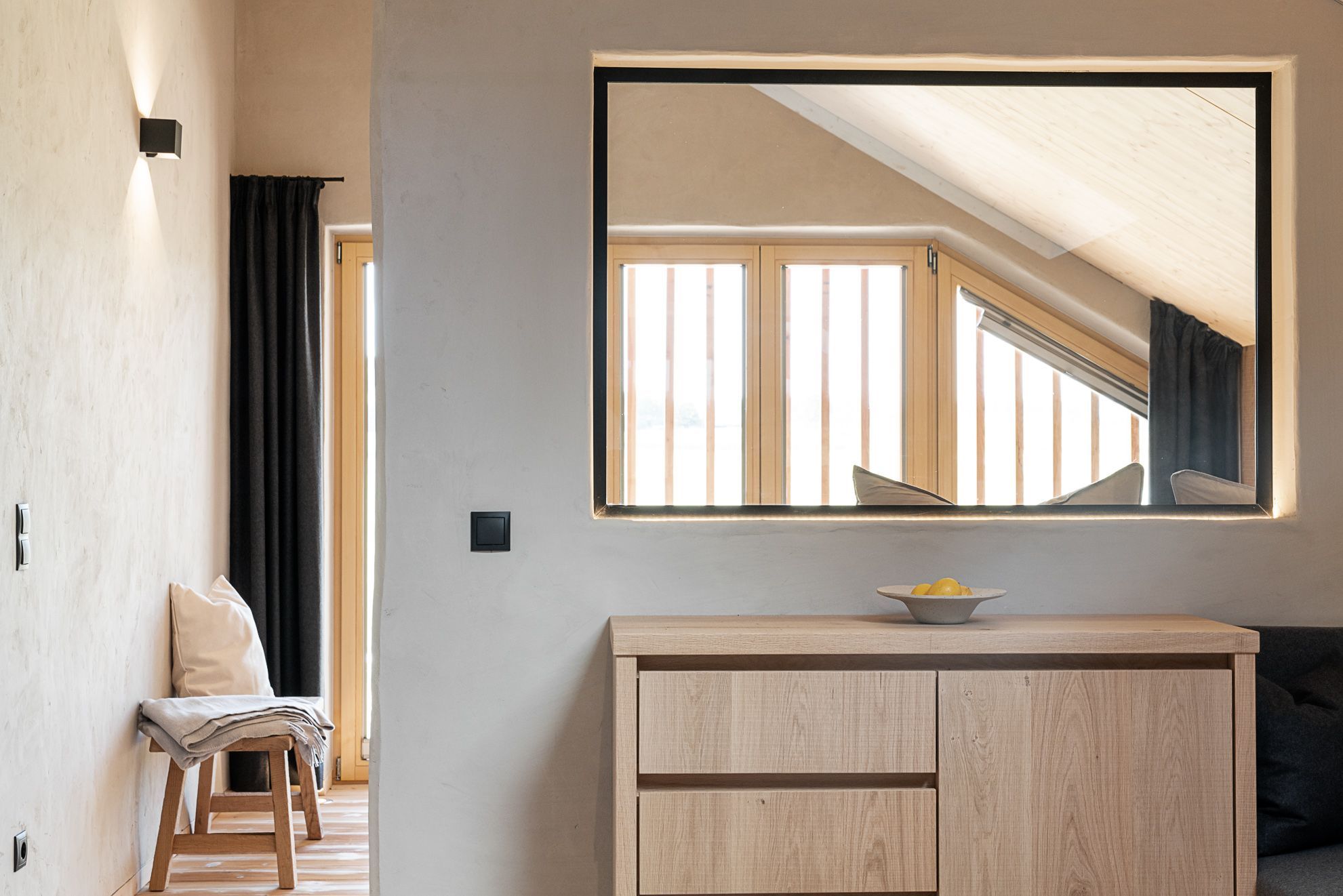 A room with a wooden cabinet, a mirror, and a view of a sloped ceiling.