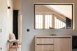 A room with a wooden cabinet, a mirror, and a view of a sloped ceiling.