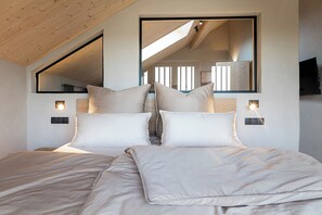 Ein Schlafzimmer mit einem großen Bett, zwei Nachttischen, einem Spiegel und einem Fernseher.