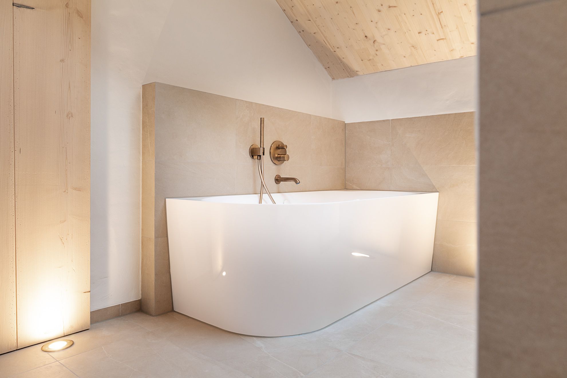 A modern bathroom with a freestanding bathtub, a wooden ceiling, and tiled walls.