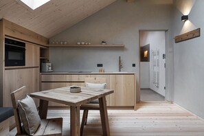 Eine kompakte Küche mit Holzschränken, einem Esstisch mit Stühlen und einem eingebauten Ofen.