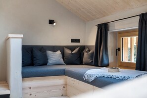 Una habitación moderna y acogedora con un sofá modular, piso de madera, una mesita con un cuenco y una ventana con cortinas.