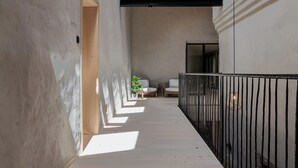 Un couloir doté d’un plancher en bois, d’une rambarde en métal noir et d’une plante en pot.