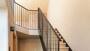 Un escalier en bois avec une rampe noire menant à une porte.