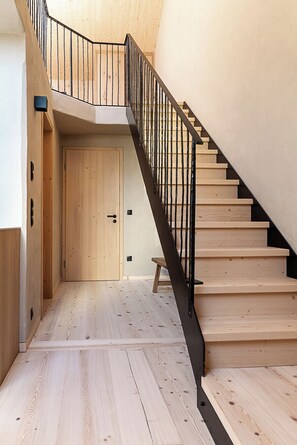 A wooden staircase with a black railing leading to a door.