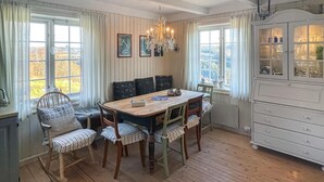 A dining area with a wooden table, striped chairs, a chandelier, and a cabinet with glass doors. - 4 bedroom cozy home in Svorkmo (Svorkmo)