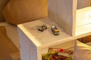 A small wooden shelf with two toy vehicles and a magazine.