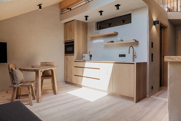 Una cucina compatta con mobili in legno, forno integrato e un piano di lavoro con lavandino.
