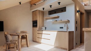 A compact kitchen with wooden cabinets, a built-in oven, and a countertop with a sink. - Ferienwohnung 5, 60qm (Eggstätt)
