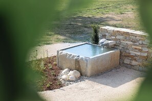 A rectangular stone pool with a stone wall on one side, surrounded by gravel and small rocks. - Ferienwohnung 5, 60qm (Eggstätt)