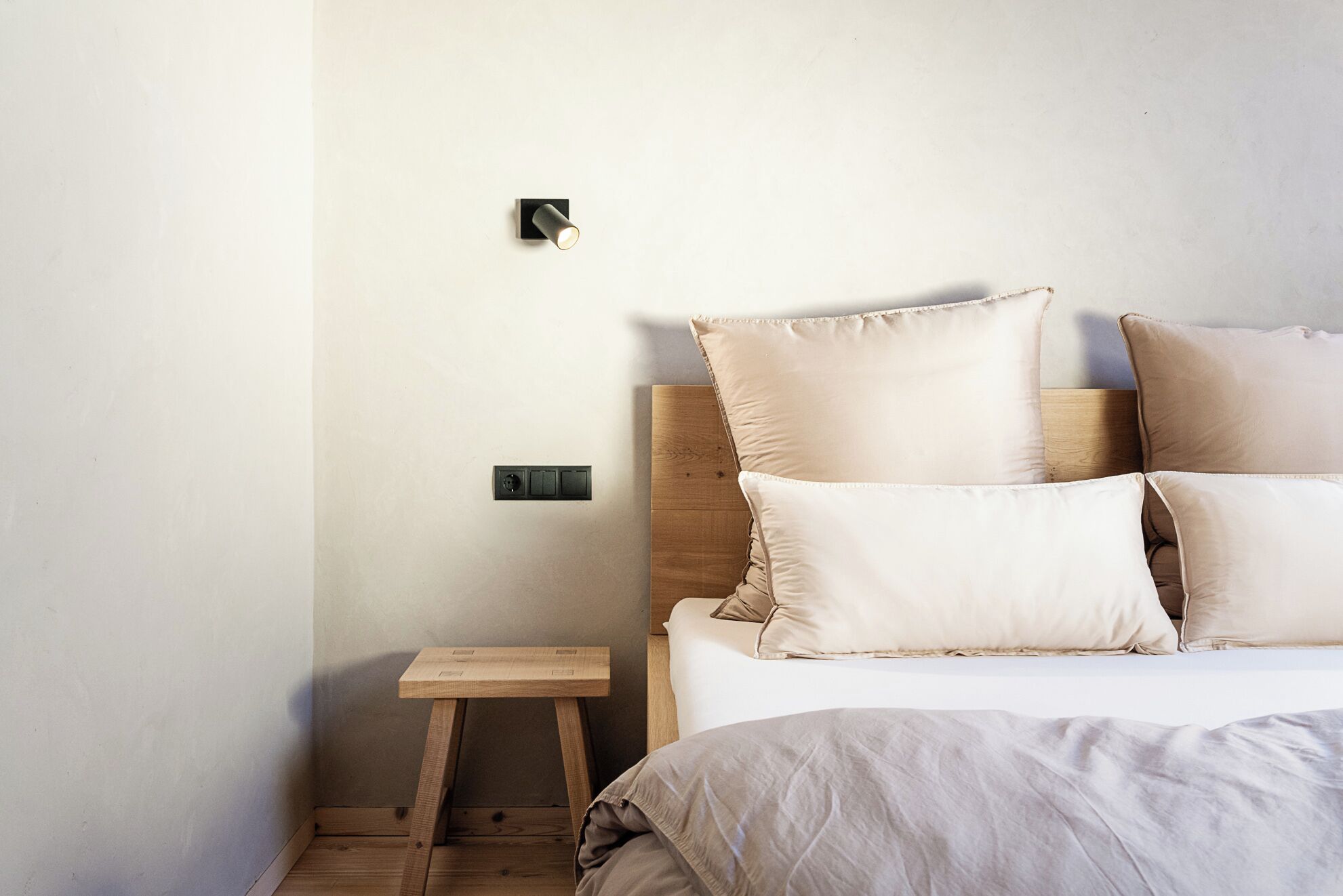 Ein Schlafzimmer mit einem Bett, Kissen, einem Nachttisch und einer Wandleuchte.