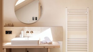 A bathroom with a round mirror, a sink, and a towel rack. - Ferienwohnung 6, 70qm (Eggstätt)