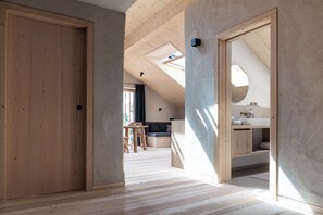 A modern interior with a wooden floor, a visible bathroom with a sink and mirror, and a skylight. - Whg 7 100qm, 2 Schlafzimmer, Balkon (Eggstätt)