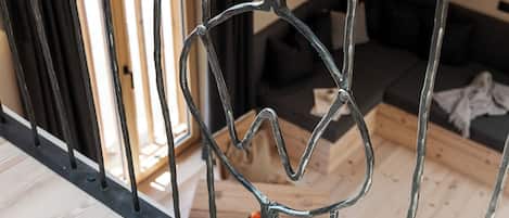 A metal railing with a heart-shaped design, a wooden floor, and a black sofa in the background.