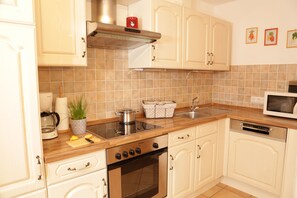 A kitchen with white cabinets, a stove, a microwave, and a sink.