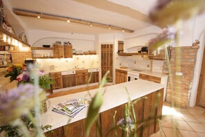 A kitchen with wooden cabinets, a central island, and a tiled backsplash. - Whg 8a Neubau, 60qm, 2 Schlafzimmer, Balkon (Eggstätt)