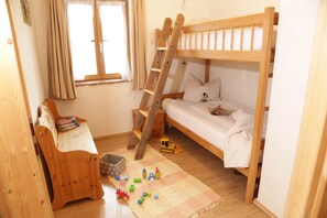A child's bunk bed with a ladder, a wooden chair, and toys on the floor.