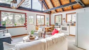 Una sala de estar acogedora con sofá, una mesa de comedor y una zona de cocina con estufa y refrigerador.