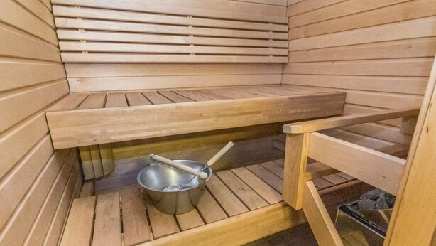 Eine Sauna mit Holzsitzen und einer Metallwanne.