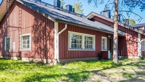 Ein rotes Holzhaus mit geneigtem Dach, weißen Fensterrahmen und einem sichtbaren Schornstein.
