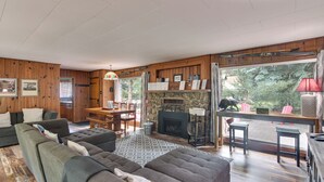 Un salon chaleureux avec une cheminée, des murs en bois et un coin repas.