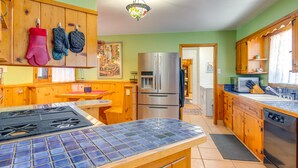 Une cuisine avec des meubles en bois, un réfrigérateur en acier inoxydable, un pare-feu en carrelage et une cuisinière à gaz.