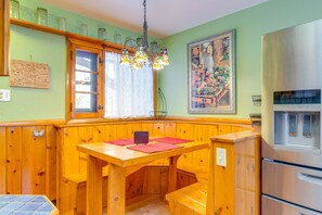 Une cuisine dotée de meubles en bois, d’un banc intégré, d’un réfrigérateur en acier inoxydable et d’un lustre en vitrail.