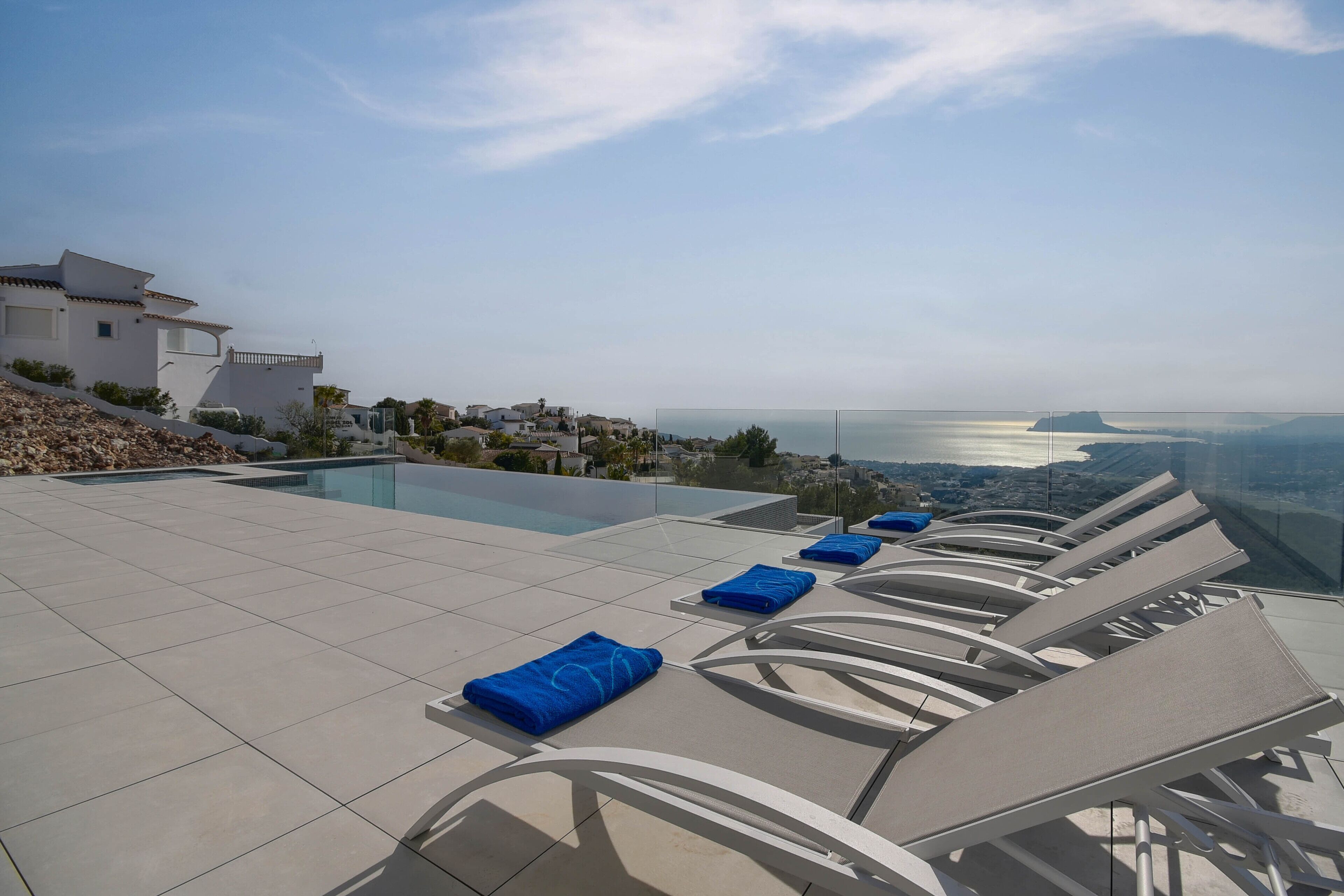 Ein Poolbereich auf dem Dach mit Liegestühlen und Blick aufs Meer.