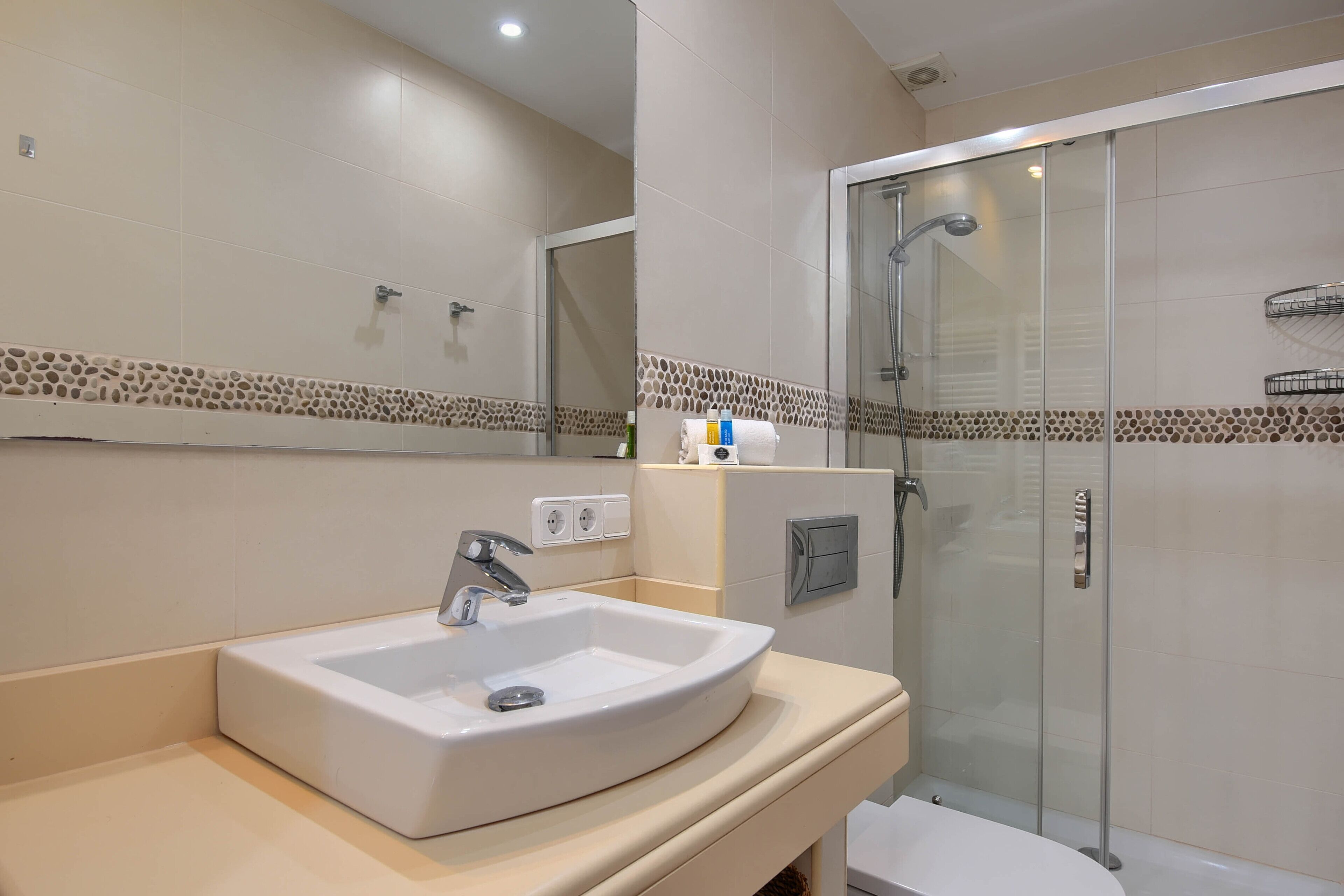 Une salle de bain avec un lavabo, un miroir et une douche.