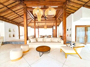 A spacious indoor area with a high ceiling, a large seating area with sofas and a coffee table, and a view of the outdoors. - Belvilla Peaceful Retreat Nelayan Beach (Canggu)
