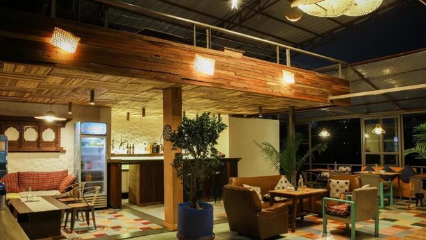A cozy indoor seating area with wooden ceiling beams, a bar counter, and a large potted plant. - Hostel Nepal Pvt. Ltd. (Pokhara)