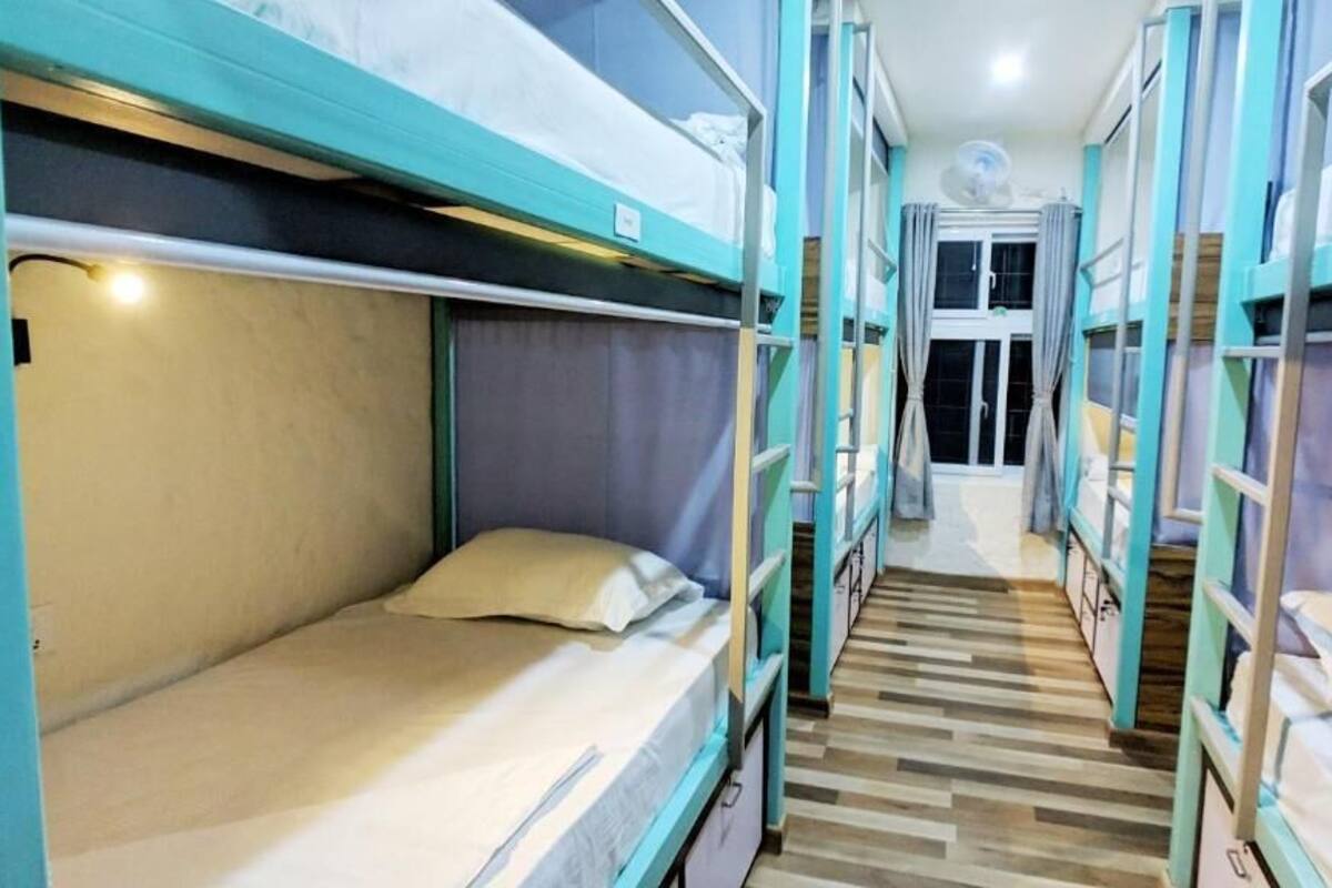 A corridor with bunk beds, wooden flooring, and a door at the end.