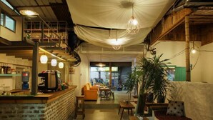A cozy cafe with a brick counter, seating area, and a staircase leading to an upper level. - Hostel Nepal Pvt. Ltd. (Pokhara)