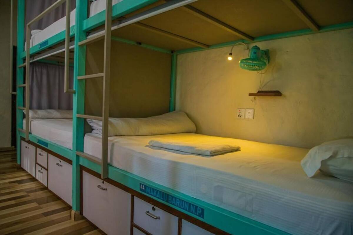 A bunk bed room with a single bed on the bottom bunk and a small desk with drawers below.