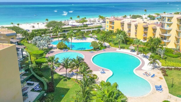 Un resort con una amplia zona de piscina, varias piscinas y una playa.