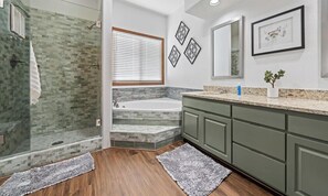 A bathroom with a glass shower, a bathtub, and a vanity with a sink.