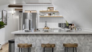 A modern kitchen with a central island, stainless steel appliances, and wooden stools. - A-frame cabin, fenced-in yard (Flagstaff)