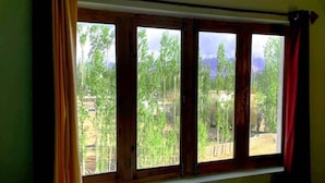 Uma janela com vista para uma área arborizada e uma cordilheira.