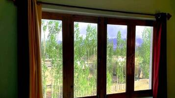 Una ventana con vistas a una zona boscosa y una cadena montañosa.